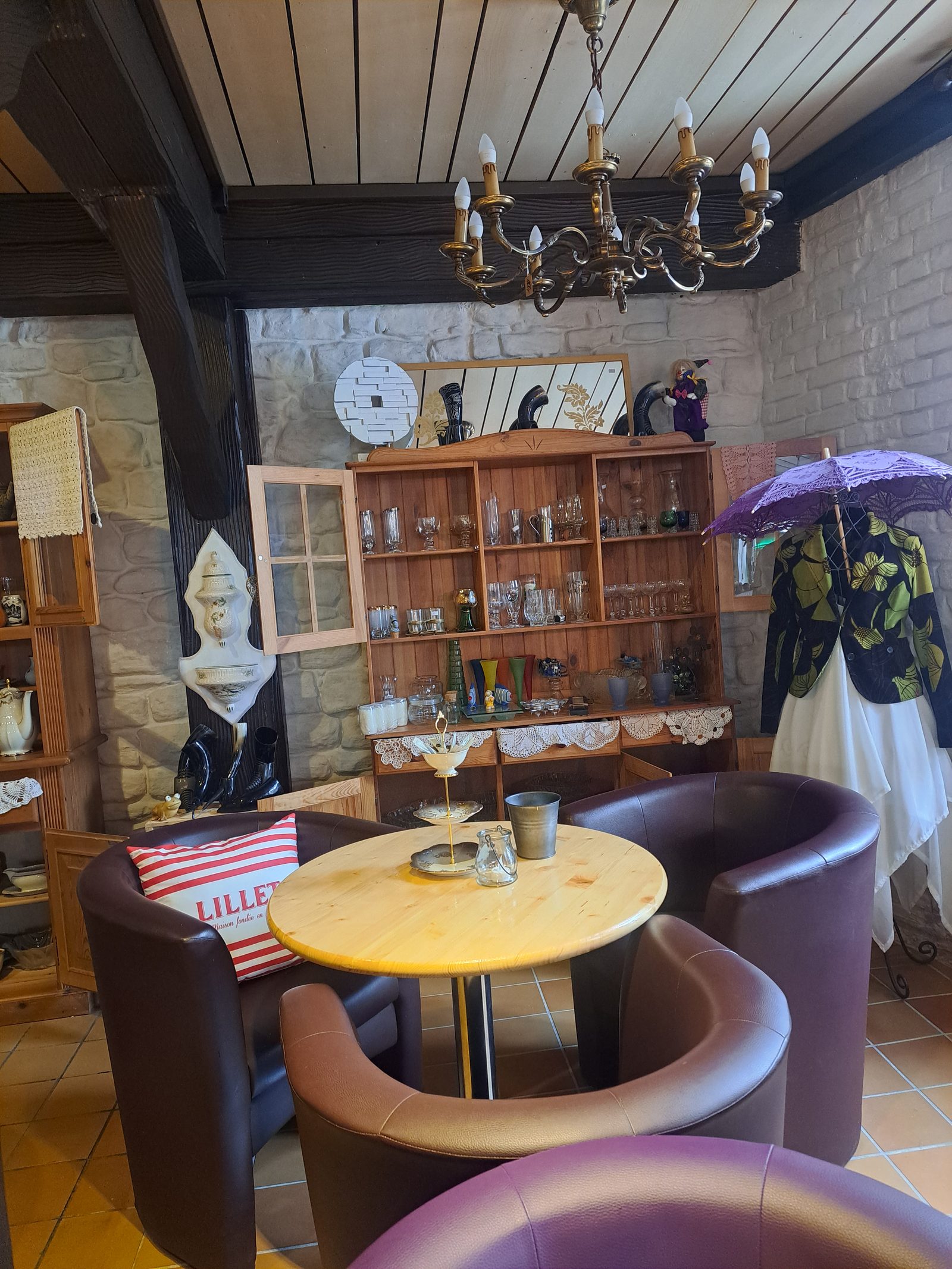 Gemütliche Sitzecke im Café von Von Mensch zu Mensch, mit Ledersesseln, rundem Holztisch und einer Vitrine im Hintergrund